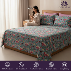 Woman sitting on a bed with floral bedding, Casa Vaas brand visible