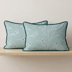 Two decorative pillows with floral pattern on a wooden shelf against a light background