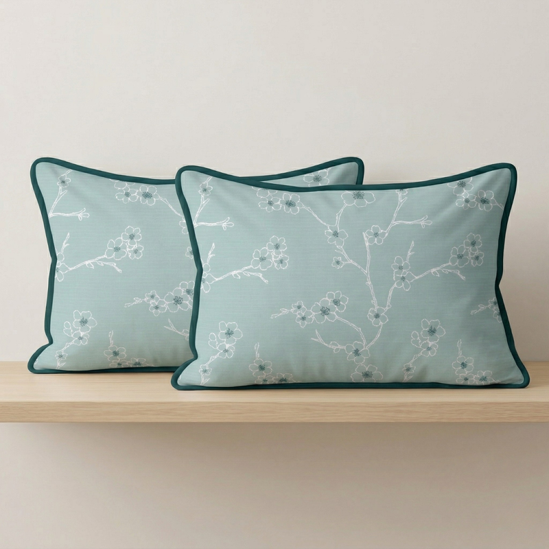 Two decorative pillows with floral pattern on a wooden shelf against a light background