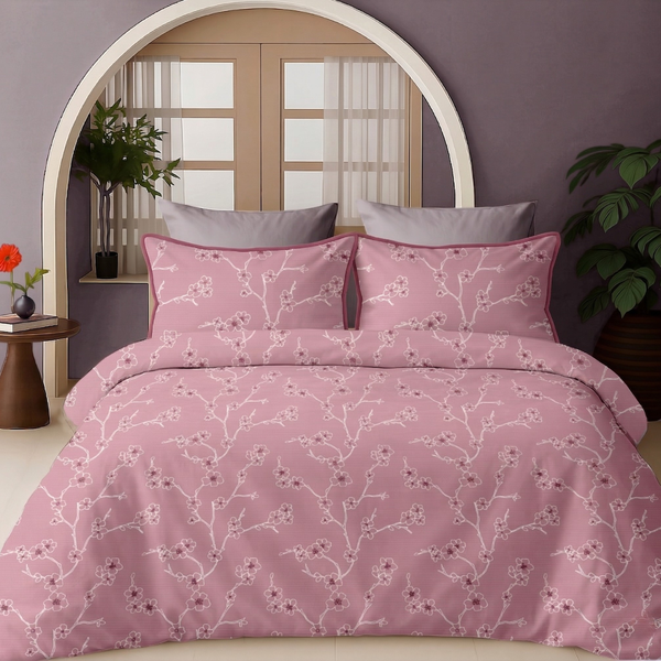 Pink floral bedding set on a bed with a purple wall and window in the background.