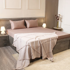 Neatly made bed with pink bedding in a bedroom setting.