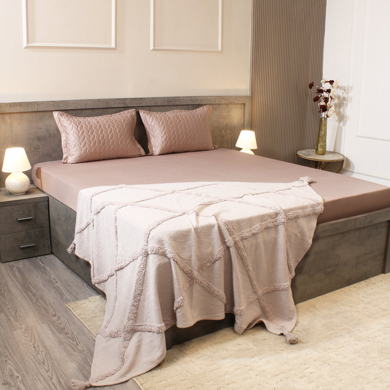 Neatly made bed with pink bedding in a bedroom setting.