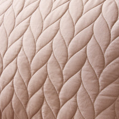 Close-up of a quilted fabric with a braided pattern in a soft pink color.