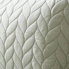 Close-up of a quilted fabric with braided pattern in light gray color.