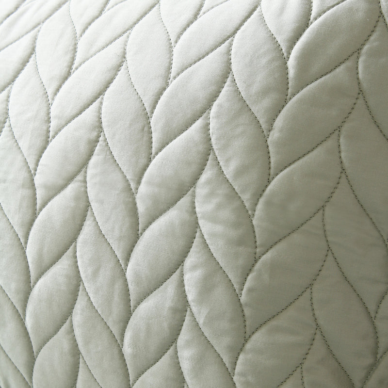 Close-up of a quilted fabric with braided pattern in light gray color.