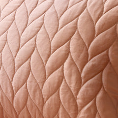 Close-up of a quilted fabric with a diamond pattern in a soft pink color.