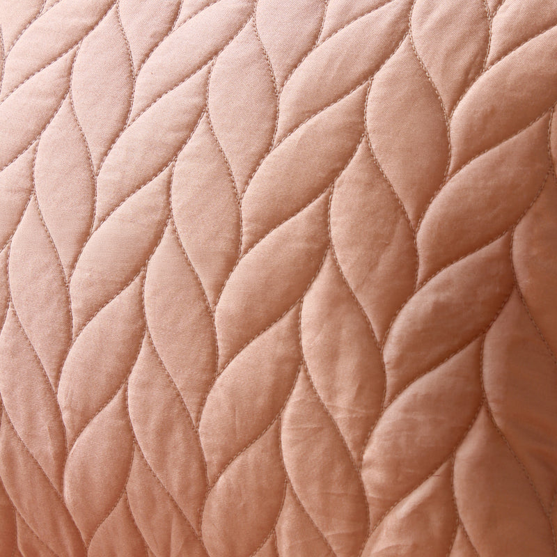 Close-up of a quilted fabric with a diamond pattern in a soft pink color.