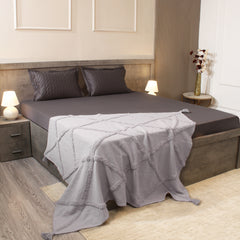 Bedroom with a bed featuring gray bedding and pillows, nightstands with lamps, and a vase on a shelf.