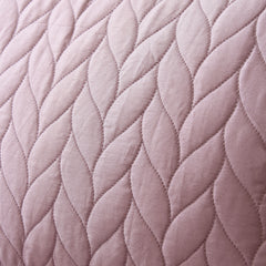 Close-up of a quilted fabric with a diamond pattern in a soft pink color.