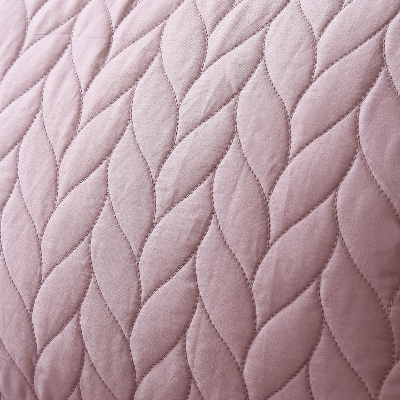 Close-up of a quilted fabric with a diamond pattern in a soft pink color.