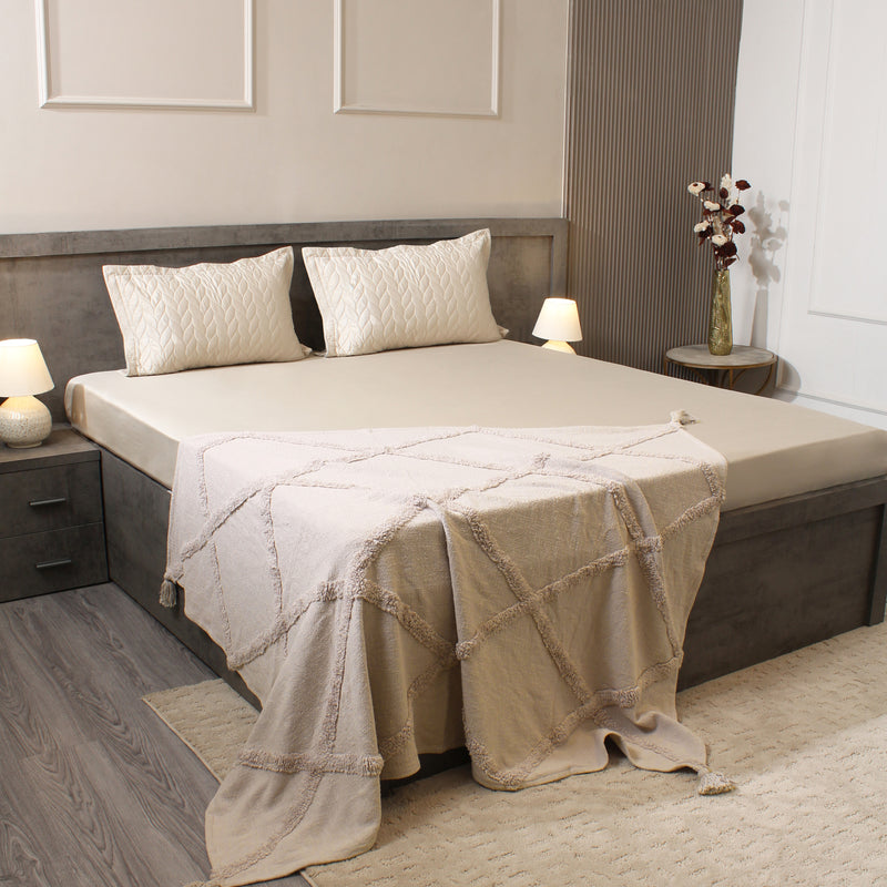 Neatly made bed with beige bedding in a bedroom setting.
