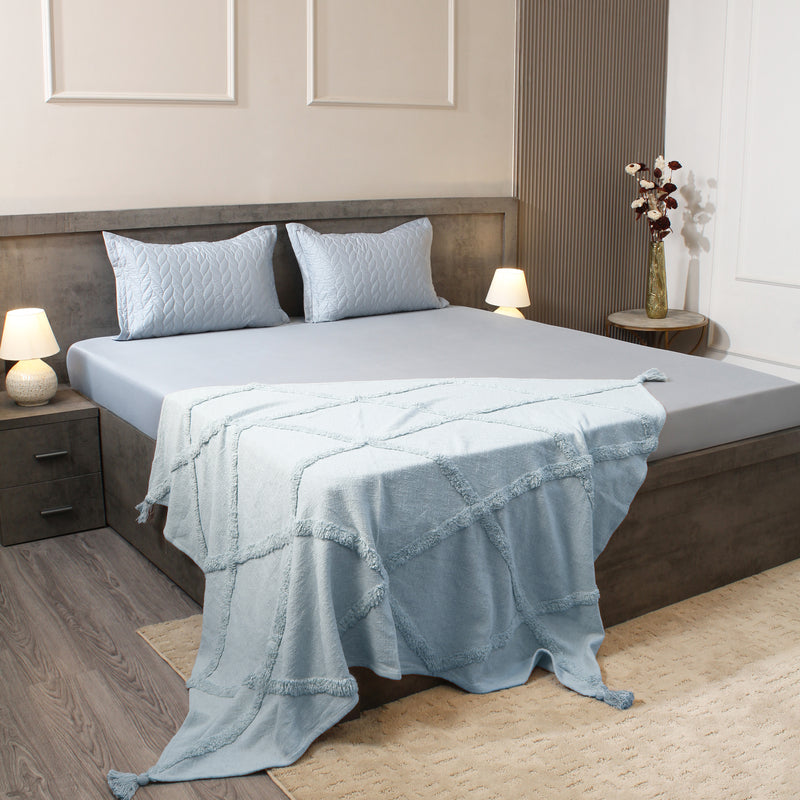 Bed with light blue bedding in a bedroom setting