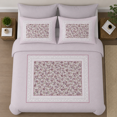 Floral patterned bedding set on a bed with decorative pillows.