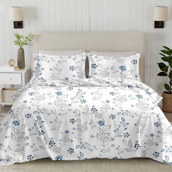 Floral-patterned bedding set on a bed in a bedroom setting with plants and lamps.