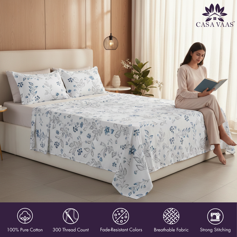 Woman reading a book by a bed with floral bedding, Casa Vaas brand visible