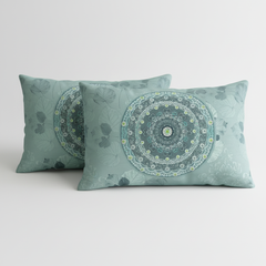 Two teal pillows with mandala patterns on a light gray background