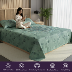 Woman sitting on a bed with a green patterned comforter in a bedroom setting.