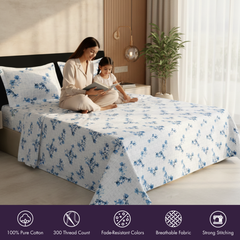 Woman and child sitting on a bed with blue floral bedding in a bright bedroom.